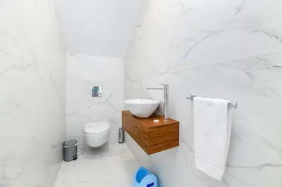 a white bathroom with a sink and a toilet at By The Beach - White Coral Villa in Protaras