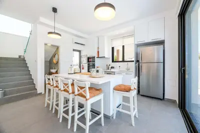 a kitchen with a white island with chairs and a refrigerator at By The Beach - Sea Pearl Villa in Protaras