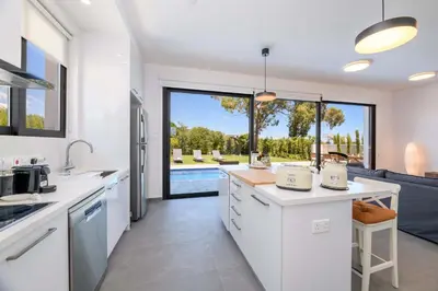 a kitchen with white cabinets and a view of a pool at By The Beach - Sea Pearl Villa in Protaras