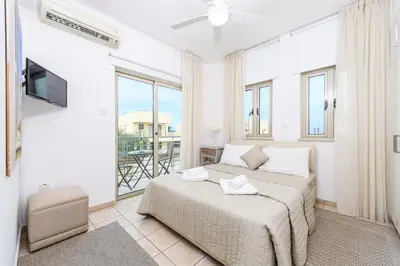 a white bedroom with a bed and a balcony at Sunrise Bay Villa #2 in Protaras