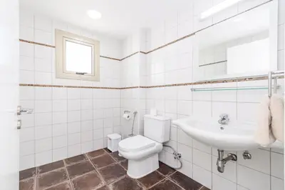 a white bathroom with a toilet and a sink at Sunrise Bay Villa #2 in Protaras