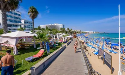 a beach with people walking down a boardwalk at Sunrise Bay Villa #3 in Protaras