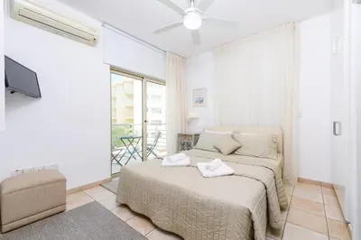 a white bedroom with a bed and a balcony at Sunrise Bay Villa #4 in Protaras