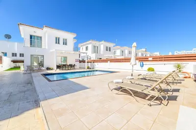 a patio with lounge chairs and a swimming pool at Sunrise Bay Villa #6 in Protaras