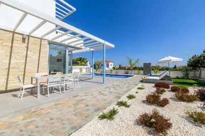 a patio with a white pergola and a table and chairs at Mylos Lifestyle Seaview Villa #15 in Protaras