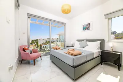 a bedroom with a bed and a chair and a window at Mylos Lifestyle Seaview Villa #15 in Protaras