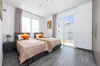 a bedroom with two beds and a large window at Green Bay Villa #15 in Protaras