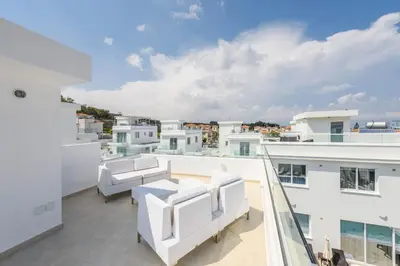 a balcony with white furniture and a view of the city at Green Bay Villa #16 in Protaras