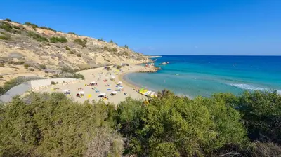 a beach with people and umbrellas and the ocean at Green Bay Villa #16 in Protaras