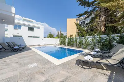 a swimming pool with two lounge chairs next to a building at Green Bay Villa #16 in Protaras