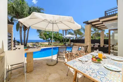 a patio with a table and an umbrella next to a pool at Villa Greco Mare #6 in Protaras
