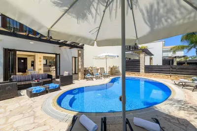 a swimming pool with an umbrella in a yard at Villa Greco Mare #6 in Protaras