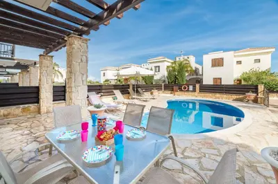 a patio with a table and chairs next to a swimming pool at Villa Greco Mare #20 in Protaras