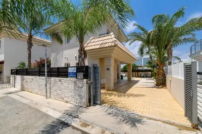a house with palm trees and a fence at Villa Clementine in Protaras