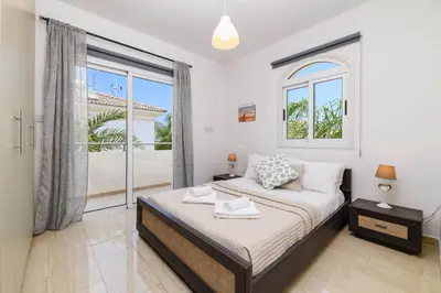 a bedroom with a bed and a large window at Villa Clementine in Protaras