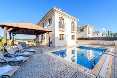 a swimming pool with lounge chairs and a house at Hanns Villa in Protaras
