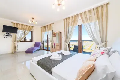 a bedroom with a white bed and a large window at Hanns Villa in Protaras
