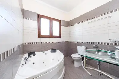 a bathroom with a tub and a toilet and a sink at Hanns Villa in Protaras