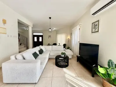 a living room with a white couch and a tv at STAY Tranquility Cove in Larnaka