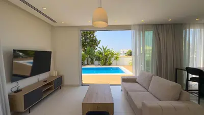 a living room with a couch and a tv and a pool at City Napa Seaview Villas - Villa 5 in Ayia Napa