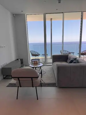 a living room with a couch and chairs and the ocean at Ayia Napa Marina Exclusive Apartment in Ayia Napa