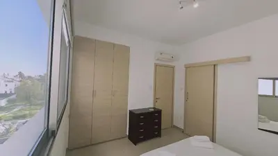 a bedroom with a bed and a large window at STAY White Petals Apartment in Larnaka
