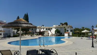 a large swimming pool with chairs and an umbrella at STAY Blissful Apartment in Protaras