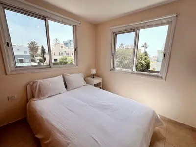 a bedroom with a white bed with two windows at KAMILA 5 in Voroklini