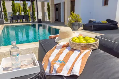 a basket of fruit and a hat on a table next to a pool at SunnyVillas-3BR New Modern Villa-Private Pool-HVN in Paralimni