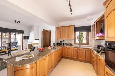 a kitchen with wooden cabinets and a large island at SunnyVillas-3BR New Modern Villa-Private Pool-HVN in Paralimni