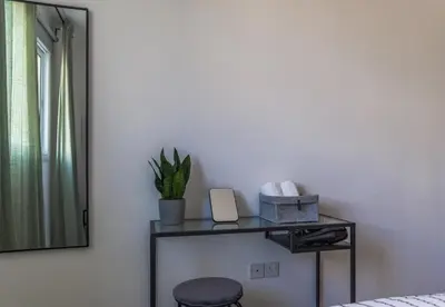 a bedroom with a table with a mirror and a stool at Creative 1br Pool view Apt with covered parking in Livadhia