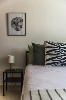 a bedroom with a bed and a table with a lamp at Creative 1br Pool view Apt with covered parking in Livadhia