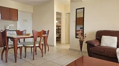a kitchen and living room with a table and chairs at Nissi Golden Sands Privileges Apt in Ayia Napa