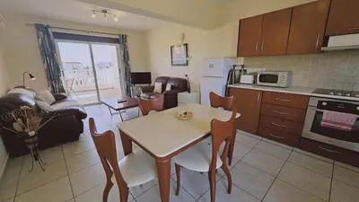 a kitchen and living room with a table and chairs at Nissi Golden Sands Privileges Apt in Ayia Napa