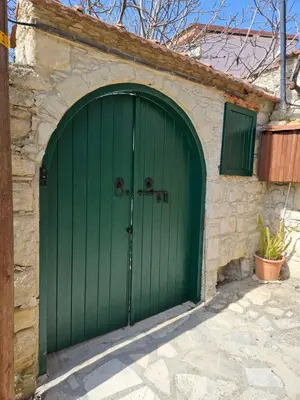 a green garage door on a stone building at The Fig Tree House in Lofou
