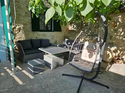 a swinging chair and a couch on a patio at The Fig Tree House in Lofou