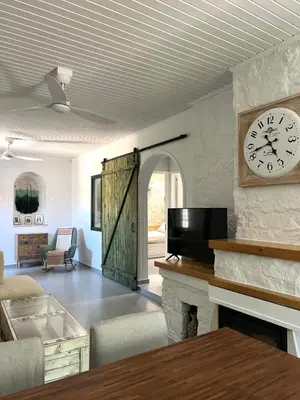 a living room with a clock on a wall at The Fig Tree House in Lofou