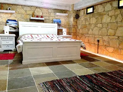 a bedroom with a bed and a stone wall at Lofou Traditional Stone House in Lofou