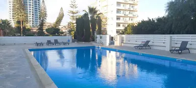 a blue swimming pool with chairs and a building at Coco De Mer 408 in Limassol