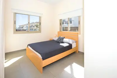 a bedroom with a bed and two windows at Bowker Apartment in Protaras