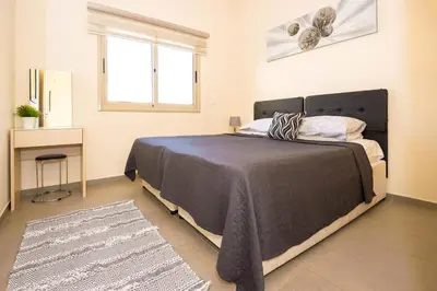 a bedroom with a bed and a desk and a window at Bowker Apartment in Protaras