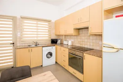 a kitchen with wooden cabinets and a washer and dryer at Bowker Apartment in Protaras