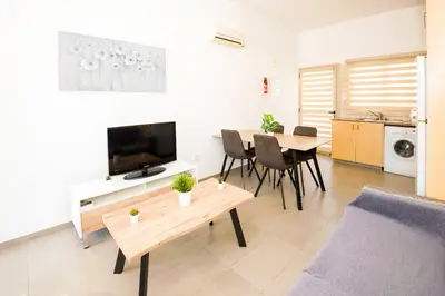 a living room with a television and a table with chairs at Bowker Apartment in Protaras
