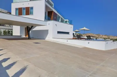 a large white house with a patio with chairs and an umbrella at Sea Pearl Seaview Villa - Oriana in Ayia Napa