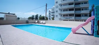 a swimming pool with a slide in front of a building at Maestro III Apartment in Larnaka