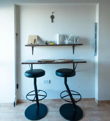 a counter with two stools in a kitchen with a table at Maestro III Apartment in Larnaka