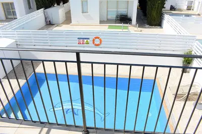 a swimming pool with a fence around it at Palm Village Escape in Protaras