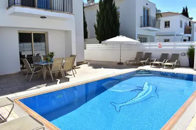 a swimming pool with dolphins painted on the side of a house at Palm Village Escape in Protaras