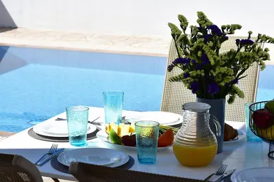 a table with plates of food and a vase of flowers at Palm Village Escape in Protaras