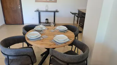a wooden table with chairs and plates and wine glasses at The Olive Grove Escape, Eleonas Apts in Sotira